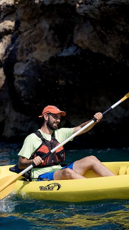 Kayakista entrando con su open kayak en una de las cuevas marinas de la costa de Els Colls-Miralpeix.