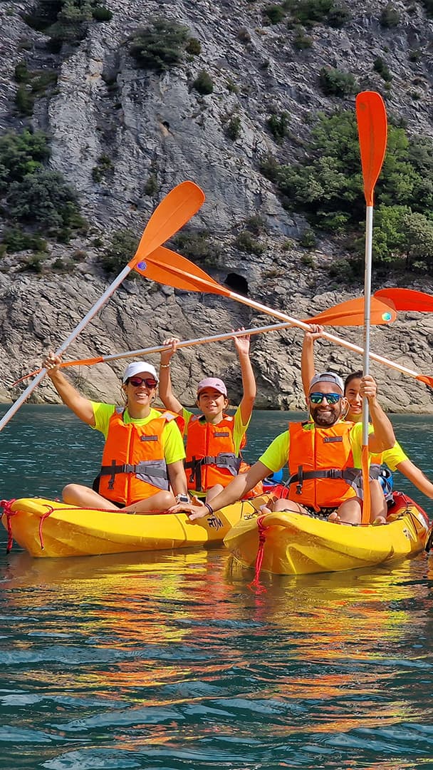 Pareja navegando tranquilamente en un kayak doble por las aguas turquesas del embalse de Escales rodeados de montañas.