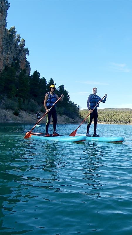 Grupo de personas con un guía practicando paddle surf en las aguas cristalinas del río Cabriel.