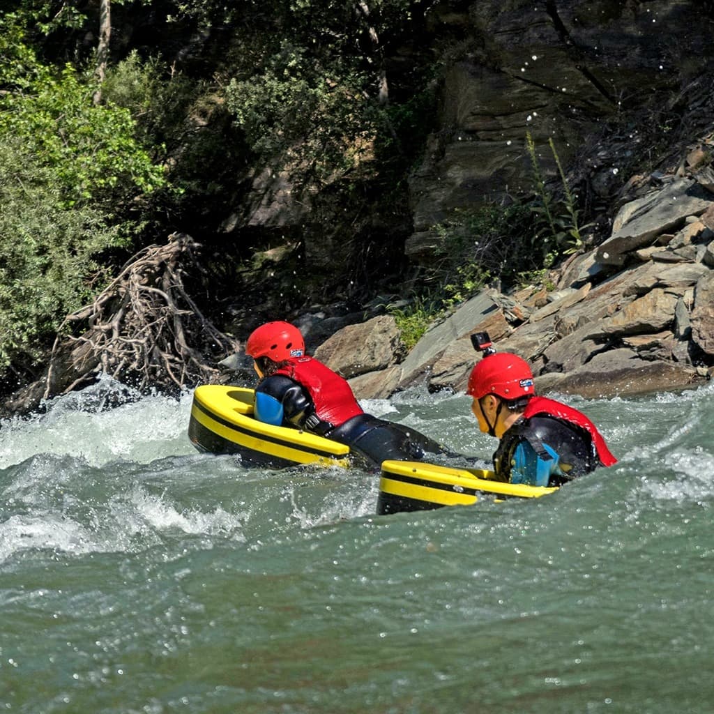 Persona equipada con casco y traje reforzado navegando por un rápido del río Noguera Pallaresa sobre una tabla de hidrospeed.