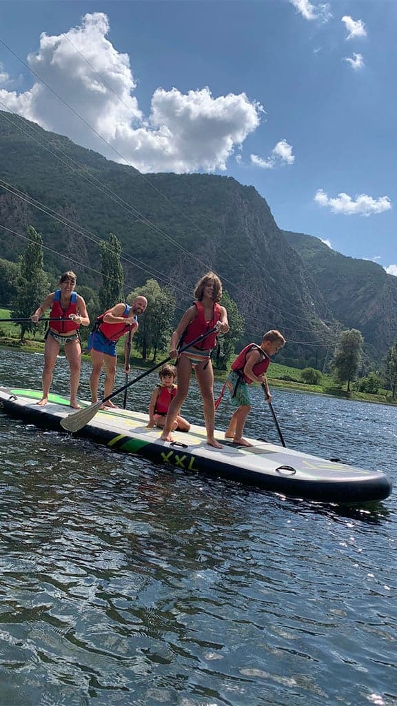 Grupo de personas coordinándose para remar sobre una tabla gigante de Big SUP en el Lago de La Torrassa.