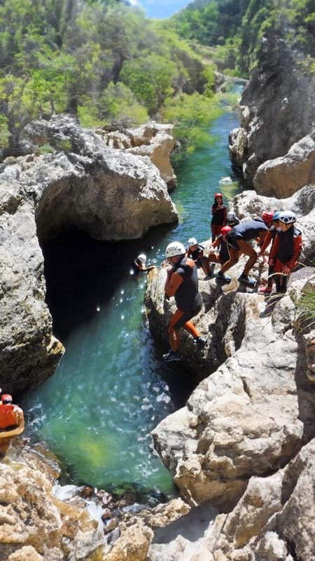 Grupo de personas con neopreno y casco preparándose para un salto en el Barranco del Río Blanco, Pirineos.